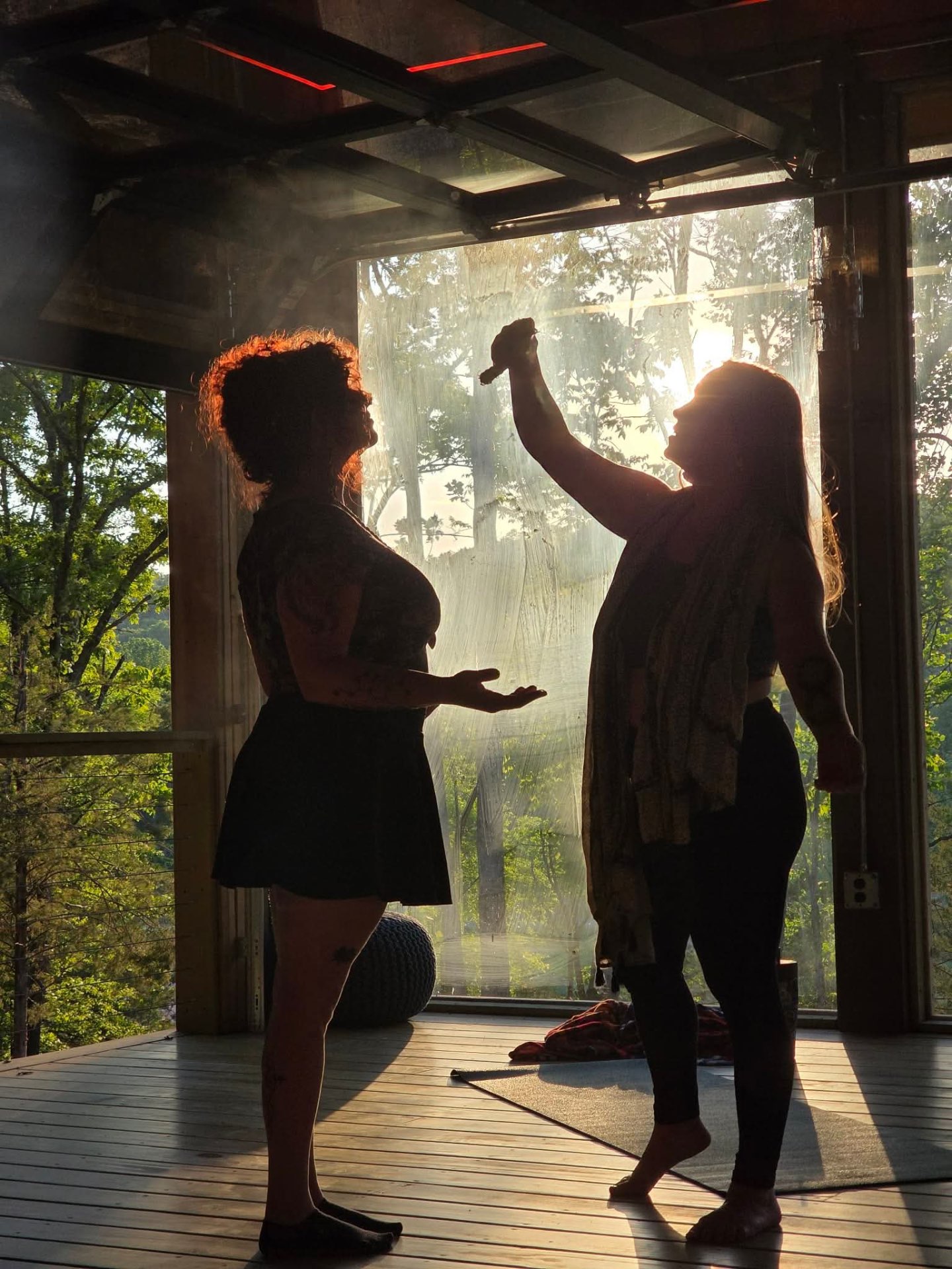 Women raising hands together in blessing at golden hour